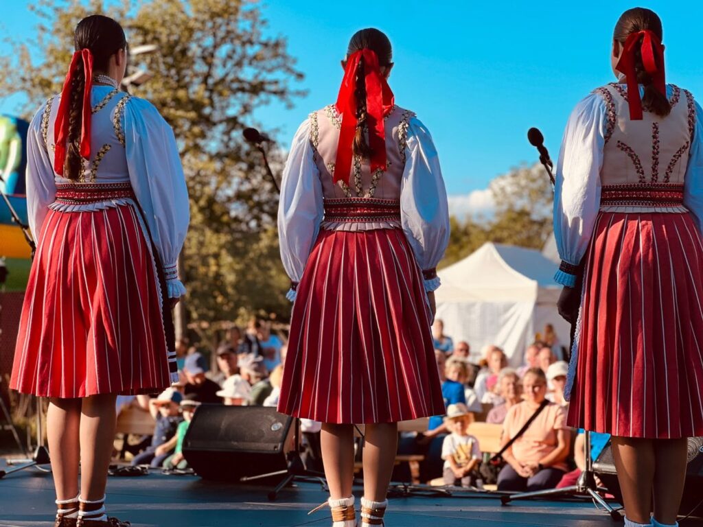 Three dancers in traditional striped skirts facing the audience at Zogrod 2026