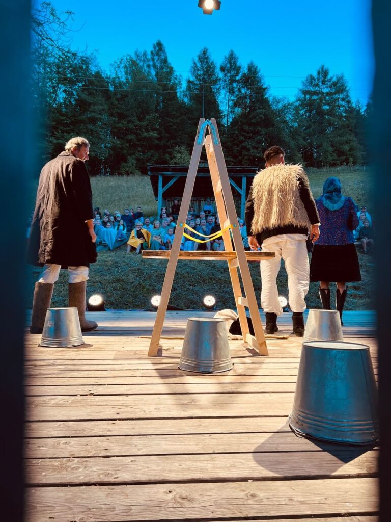 Two actors and a ladder on the Zogrod stage at dusk